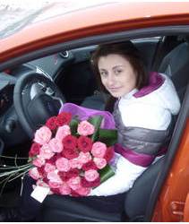 Букет роз с зеленью и в сетке в руках у автомобилистки